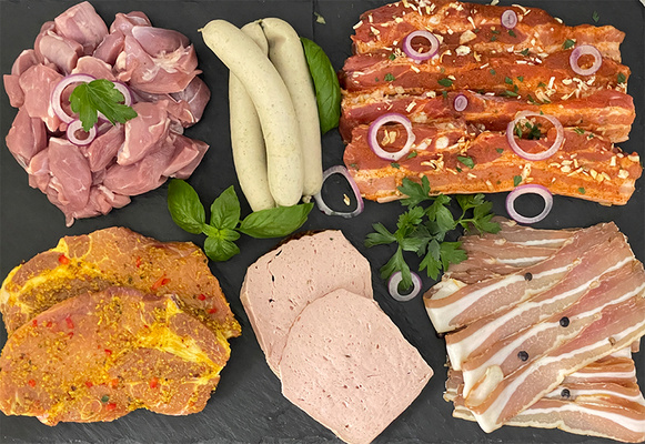 KI generiert: Eine Auswahl an verschiedenen Fleischsorten und Wurst auf einer dunklen Platte.
