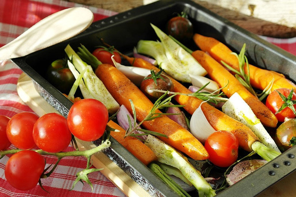 KI generiert: Ofengemüse mit Karotten, Zwiebeln, Tomaten und Kräutern in einer Backform, dekoriert mit frischen Tomaten.