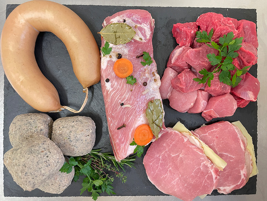 KI generiert: Verschiedene Fleischsorten auf einer Schieferplatte, dekoriert mit Gewürzen und Kräutern.