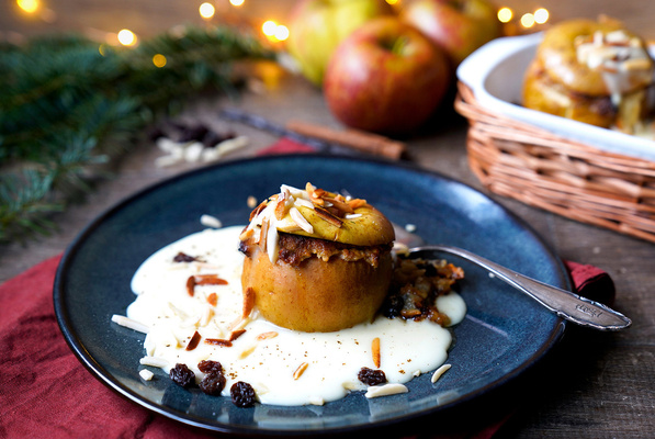 KI generiert: Ein Bratapfel auf Vanillesoße, garniert mit Mandeln und Rosinen, auf einem Teller.