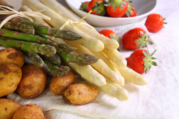 KI generiert: Spargel, Kartoffeln und Erdbeeren auf einem weißen Tuch arrangiert.