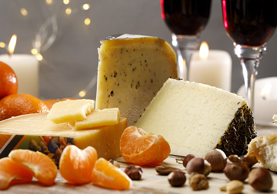 KI generiert: Käseplatte mit Mandarinen, Nüssen und Rotweingläsern im Hintergrund.